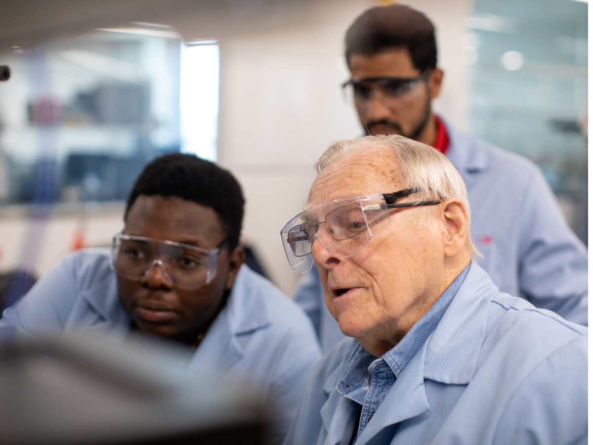 Students and a faculty member wearing lab safety glasses and coats