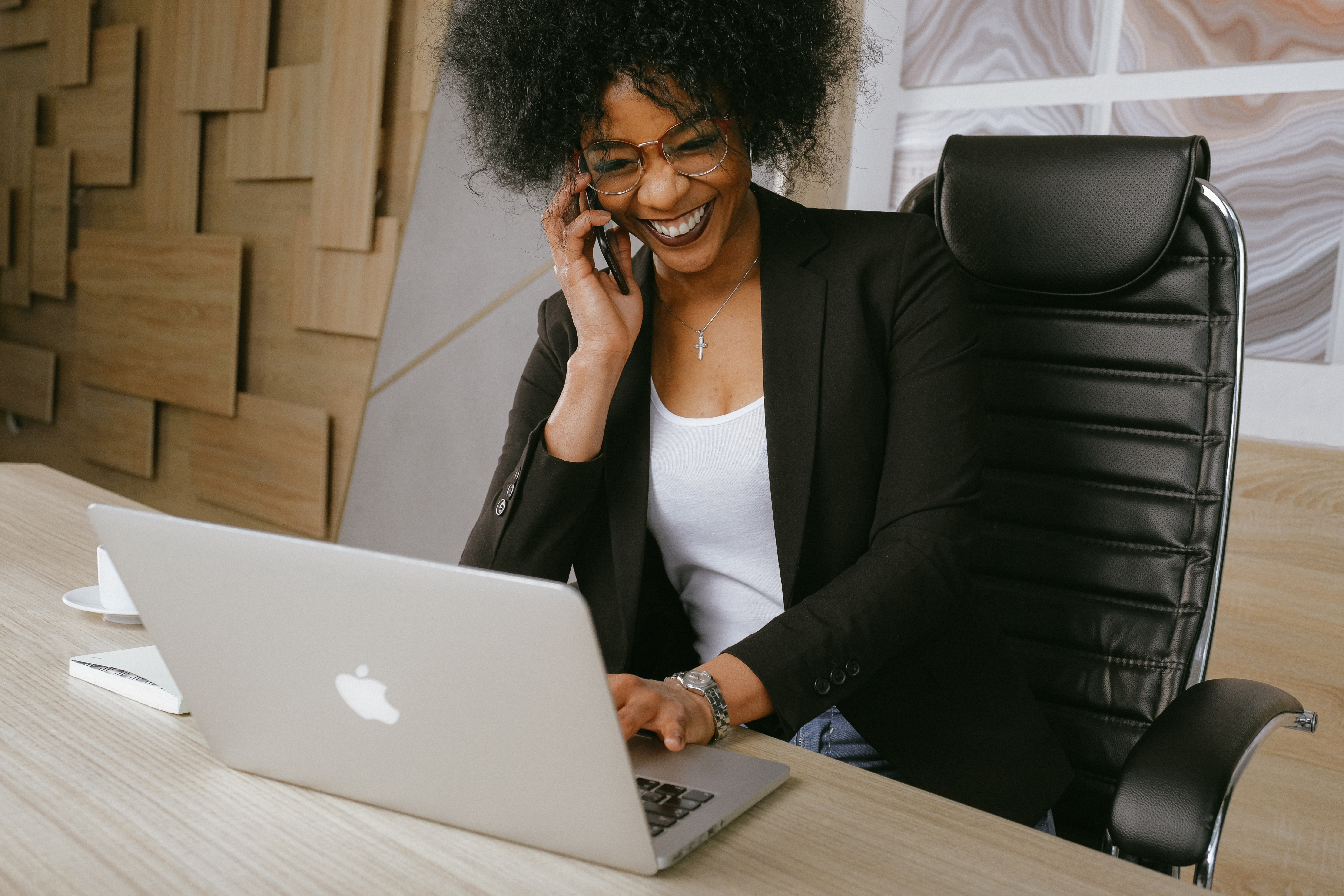 Person sitting at desk and talking on the phone with a laptop
